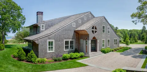 Down a winding country road, this house and its entry are designed to be seen from the road, but do not face it. The driveway crosses in front of the entry and leads to garage doors concealed to the public. The house is based on the classic Shingle Style, but is very horizontal, with a broad gable and big roof overhangs.