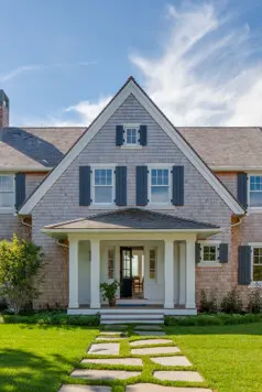 Welcome! The shingle-style Cape home has a shallow entry porch.