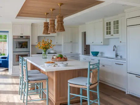 The kitchen features a wood tray ceiling above the island. The island cabinetry has a light finish
on walnut with a two-inch-thick slab of leathered White Rhino marble on top.