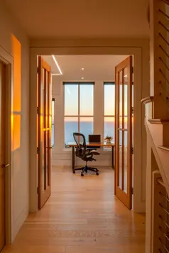 Looking from the entry, through the hallway, to the office, and out to the ocean view with the sun setting.