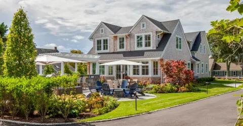 A new patio, outdoor kitchen, pergola, and firepit create seamless indoor-outdoor living while preserving open yard space for gathering and play.
