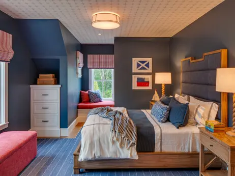 A nautical bedroom on the second floor. Built-in drawers, a built-in window seat, and a wallpapered ceiling add special touches to the space.